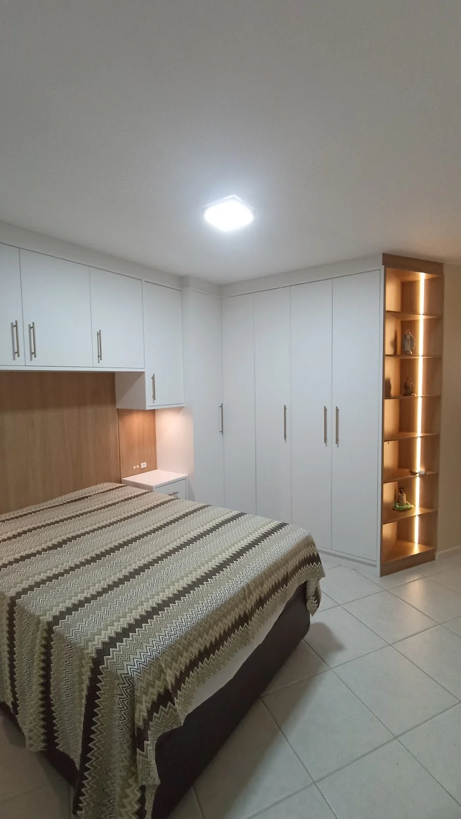 Quarto planejado com guarda-roupa branco e nicho de madeira iluminado