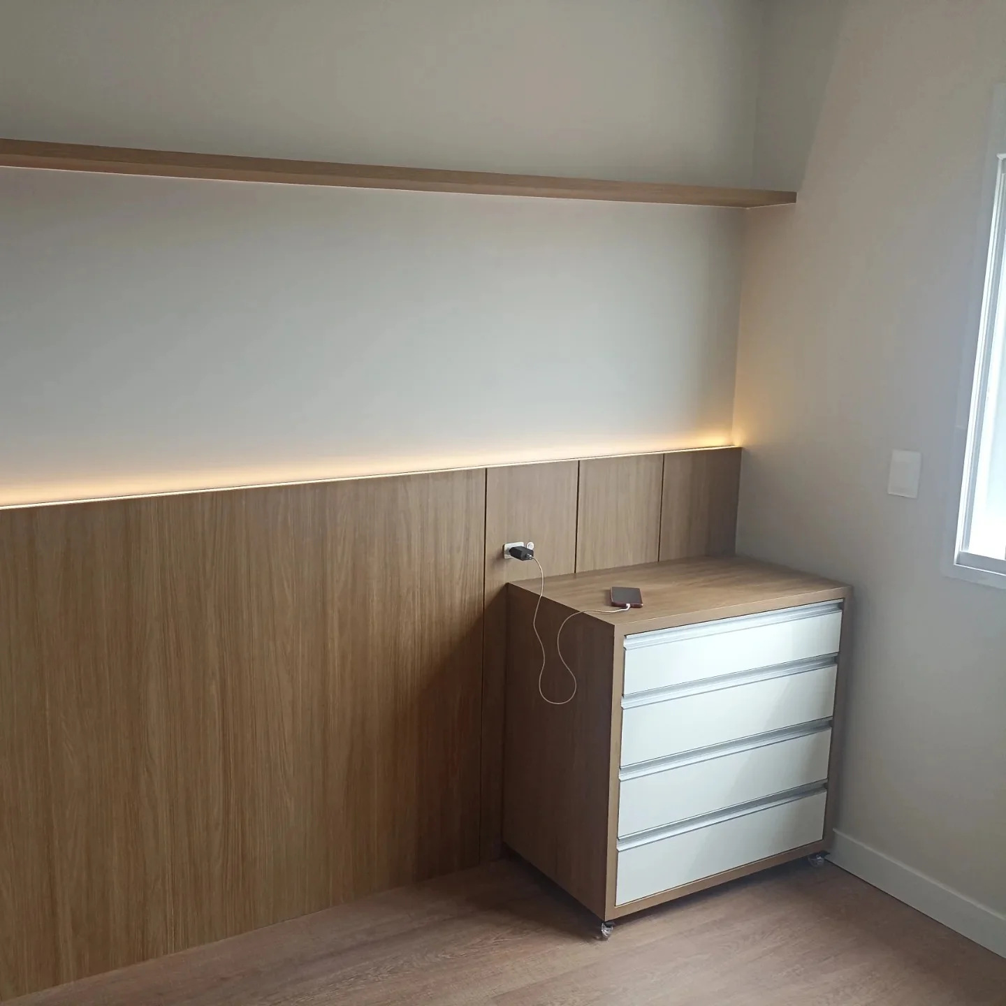 Quarto com cabeceira planejada em madeira e iluminação embutida